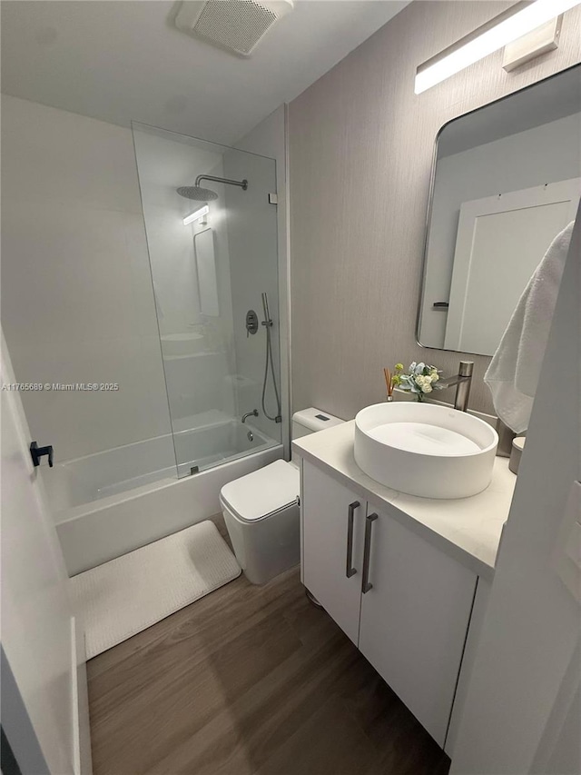 full bath with visible vents, toilet, tub / shower combination, vanity, and wood finished floors