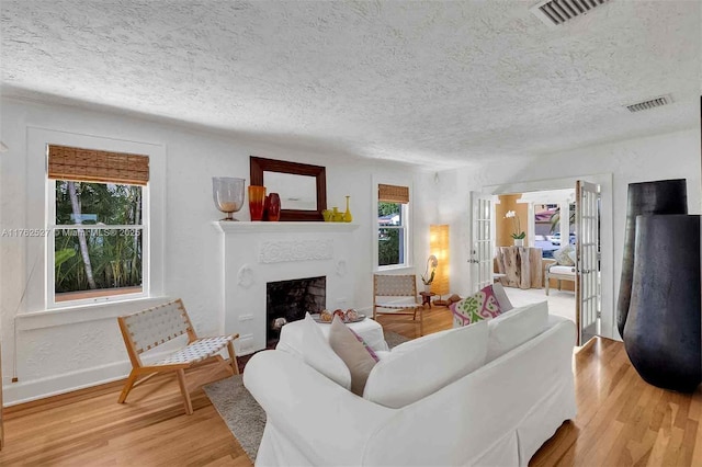 living area with a fireplace, visible vents, and light wood finished floors