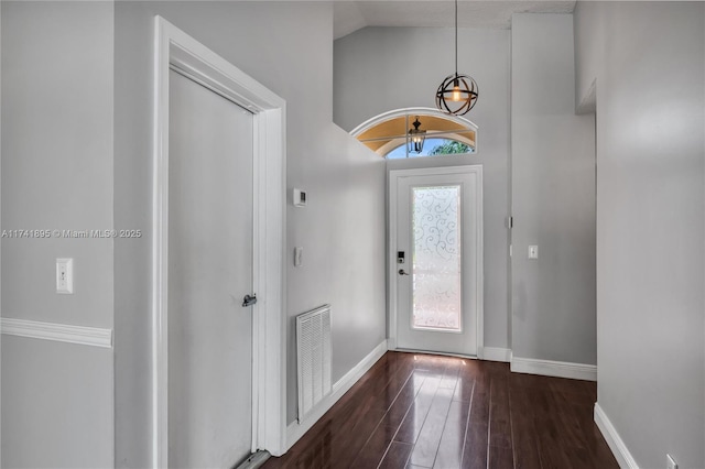 entryway featuring visible vents, baseboards, a notable chandelier, dark wood finished floors, and lofted ceiling