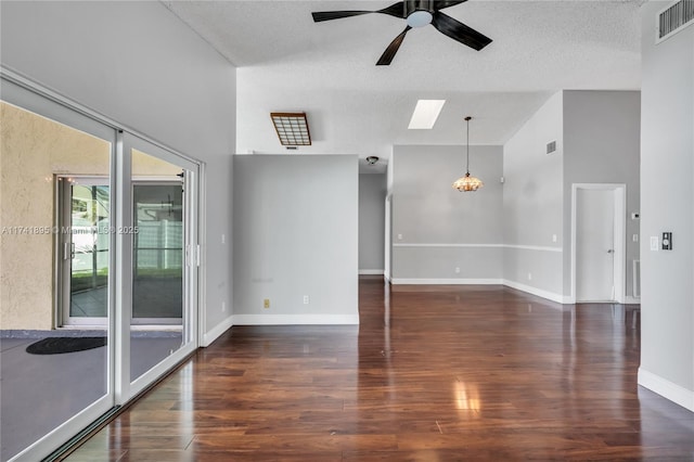 unfurnished room with ceiling fan with notable chandelier, wood finished floors, baseboards, and visible vents