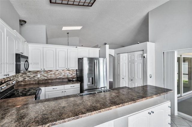 kitchen featuring vaulted ceiling, dark countertops, decorative backsplash, stainless steel appliances, and a sink