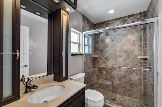 full bathroom featuring toilet, a stall shower, and vanity