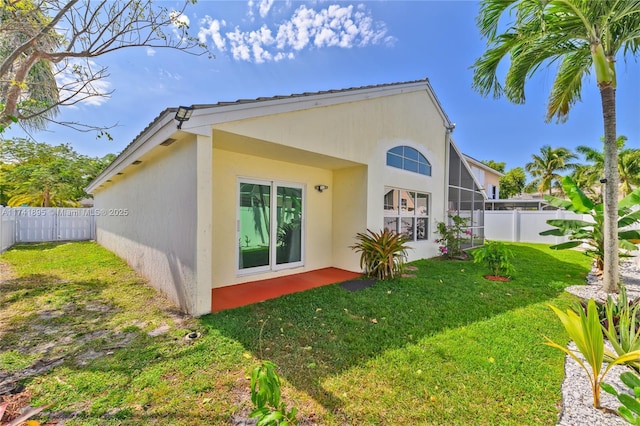 back of property featuring a fenced backyard, a lanai, a lawn, and stucco siding