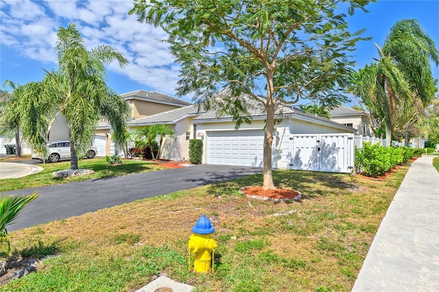 view of front facade featuring stucco siding, aphalt driveway, a tile roof, a garage, and fence