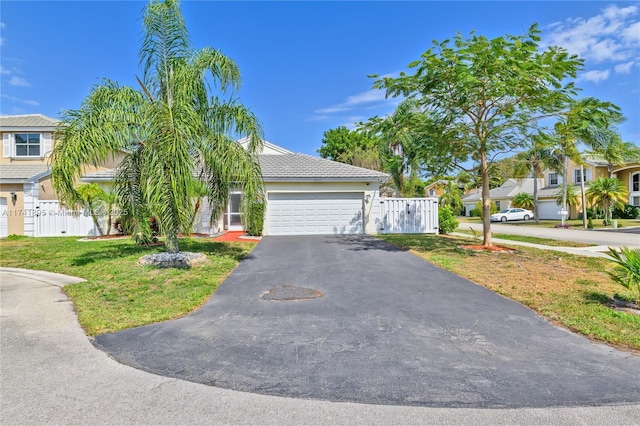 obstructed view of property with aphalt driveway, stucco siding, fence, and an attached garage