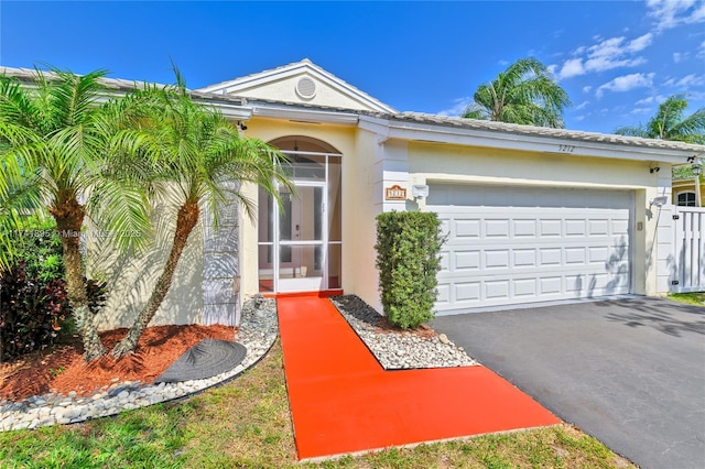 view of front facade featuring aphalt driveway, stucco siding, and an attached garage