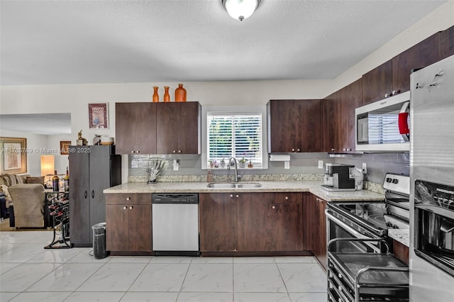 kitchen featuring dark brown cabinetry, appliances with stainless steel finishes, marble finish floor, and a sink