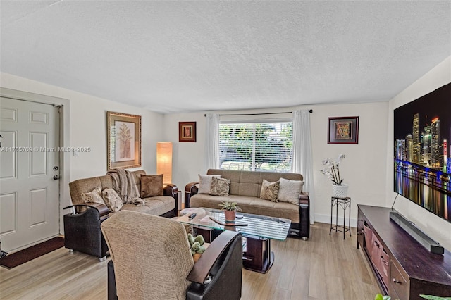 living room featuring light wood finished floors, a textured ceiling, and baseboards
