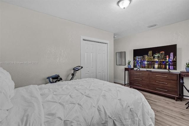 bedroom with light wood-style flooring, a closet, and visible vents