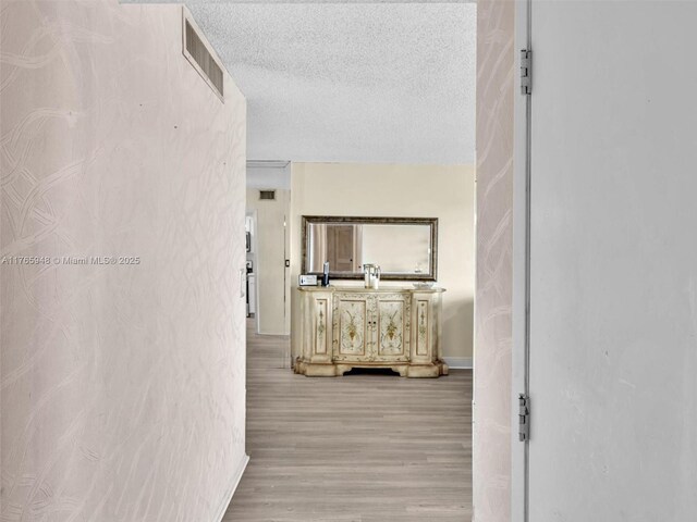 800 NE 195th St Unit 716, Miami, FL 33179 - corridor with visible vents, baseboards, a textured ceiling, and light wood-style flooring