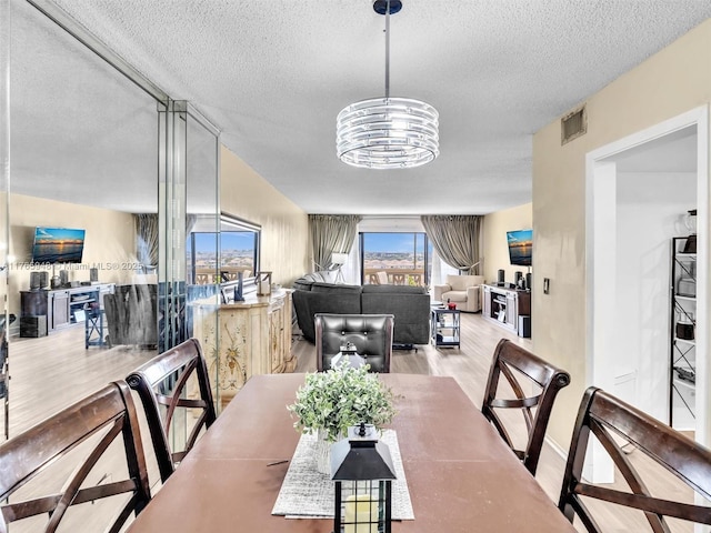 800 NE 195th St Unit 716, Miami, FL 33179 - dining area featuring visible vents, a notable chandelier, wood finished floors, and a textured ceiling