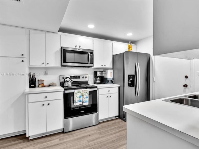 800 NE 195th St Unit 716, Miami, FL 33179 - kitchen featuring white cabinetry, light countertops, light wood-style floors, and appliances with stainless steel finishes