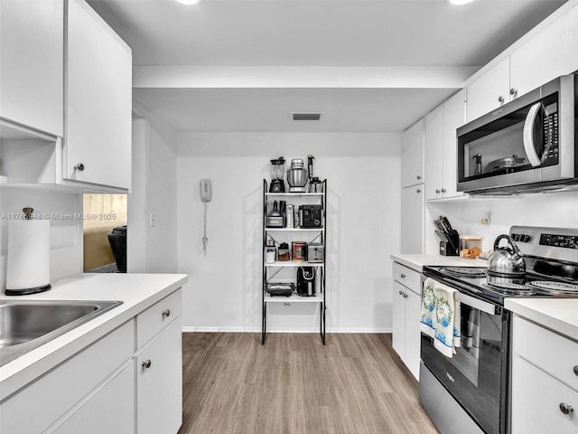 800 NE 195th St Unit 716, Miami, FL 33179 - kitchen featuring visible vents, light wood-style flooring, stainless steel appliances, light countertops, and white cabinets