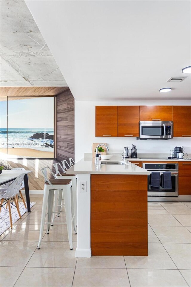kitchen with visible vents, a sink, stainless steel appliances, light countertops, and brown cabinets