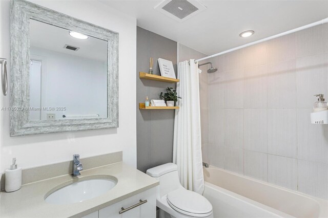 bathroom featuring visible vents, toilet, vanity, and shower / tub combo with curtain
