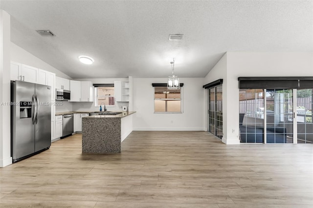 kitchen featuring a sink, open floor plan, white cabinetry, stainless steel appliances, and lofted ceiling
