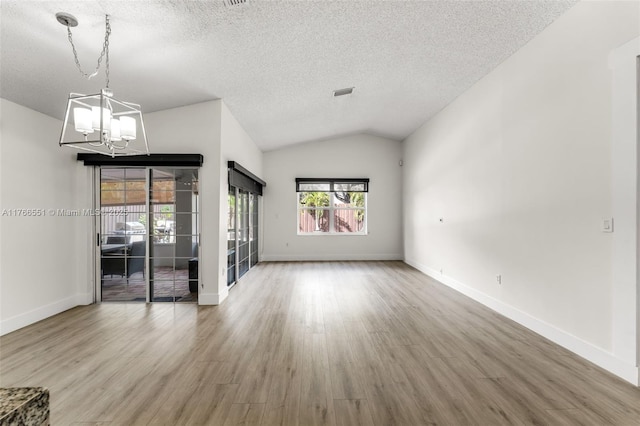 spare room featuring wood finished floors, a textured ceiling, lofted ceiling, and a chandelier