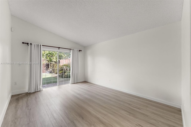 empty room with baseboards, lofted ceiling, light wood-style floors, and a textured ceiling