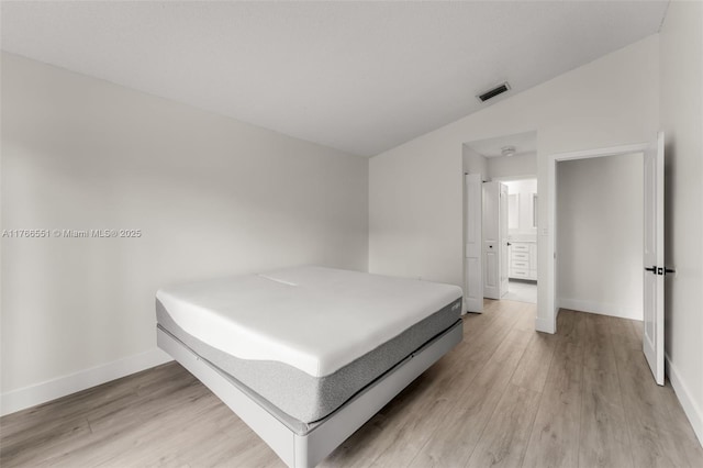 bedroom with visible vents, baseboards, light wood-style floors, and vaulted ceiling