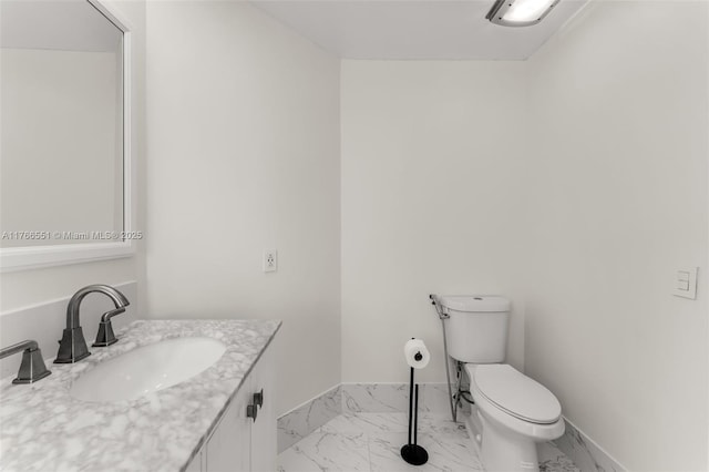 bathroom featuring baseboards, toilet, marble finish floor, and vanity