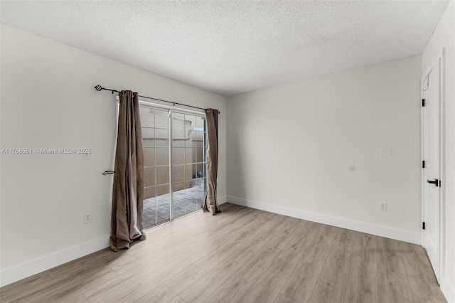 unfurnished room with light wood-style flooring, a textured ceiling, and baseboards