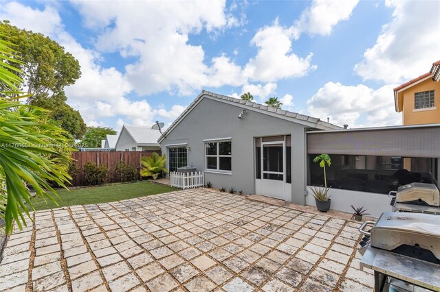 rear view of house featuring a patio area, stucco siding, a yard, and fence