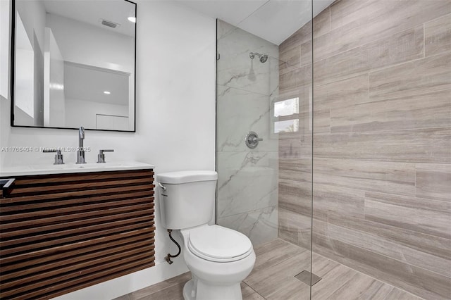 bathroom with vanity, toilet, and a tile shower