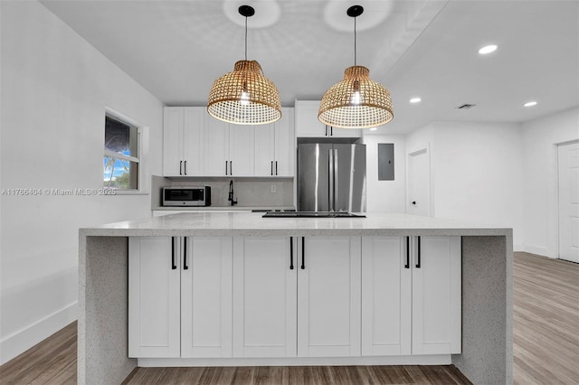 kitchen featuring visible vents, stainless steel appliances, white cabinets, light wood-type flooring, and a center island