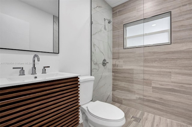 bathroom with toilet, a stall shower, and vanity