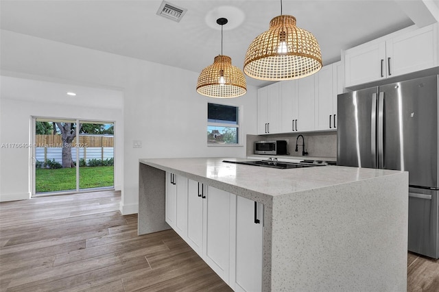 kitchen with stainless steel appliances, light stone countertops, visible vents, and light wood finished floors