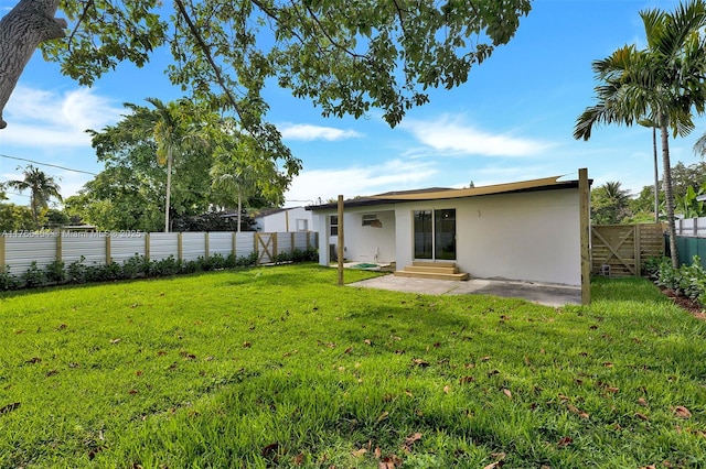 back of house featuring a yard, a fenced backyard, stucco siding, and entry steps