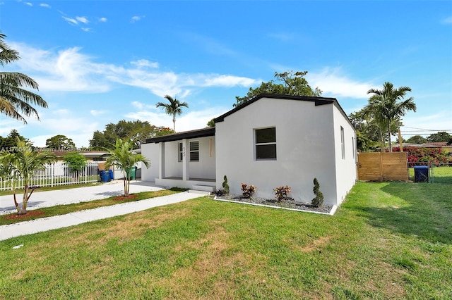 view of front of house with concrete driveway, fence, a front lawn, and stucco siding