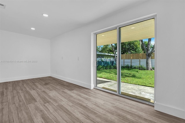 spare room with recessed lighting, wood finished floors, visible vents, and baseboards