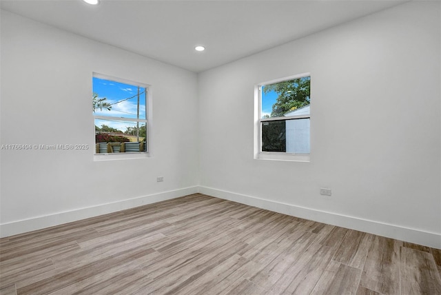 empty room with light wood finished floors, plenty of natural light, and baseboards