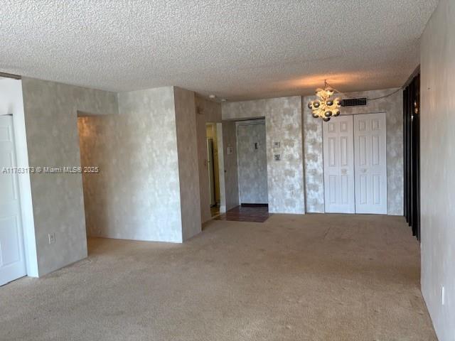 3701 N Country Club Dr Unit 207, Aventura, FL 33180 - empty room with carpet floors, a textured ceiling, a chandelier, and visible vents