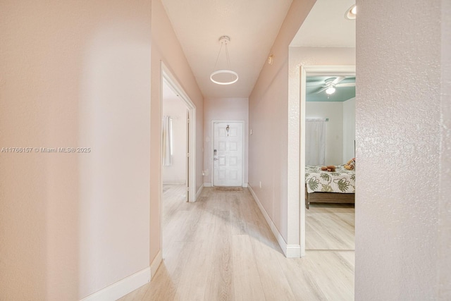 hall with baseboards and wood finished floors