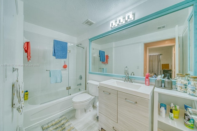 full bath with shower / bath combination with glass door, vanity, toilet, visible vents, and a textured ceiling