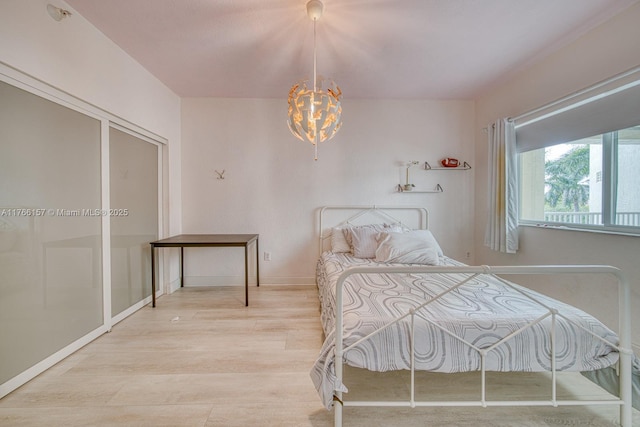 bedroom with baseboards, wood finished floors, and a notable chandelier