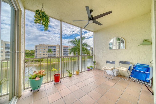 unfurnished sunroom with a ceiling fan, a water view, and a textured wall