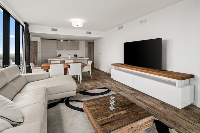 living room featuring visible vents, baseboards, and dark wood-style floors