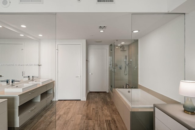 bathroom featuring wood finished floors, visible vents, a sink, a shower stall, and a bath