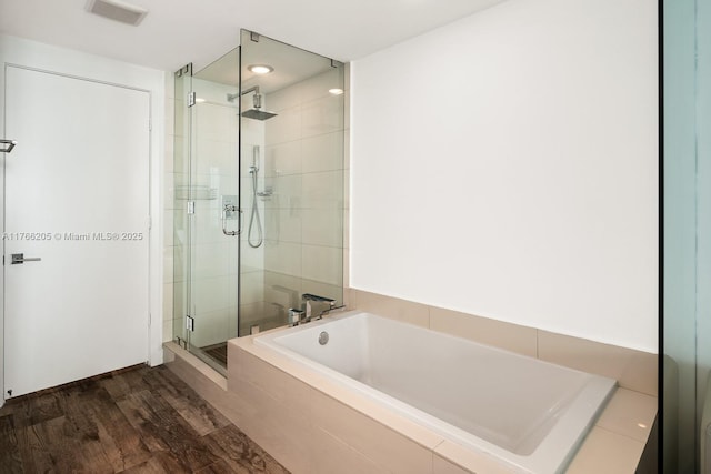 full bathroom with visible vents, a shower stall, a garden tub, and wood finished floors