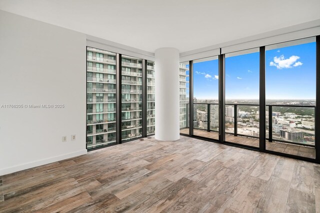 spare room featuring wood finished floors, baseboards, and expansive windows
