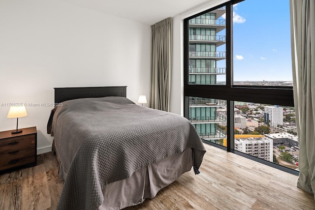 bedroom featuring floor to ceiling windows, multiple windows, and wood finished floors