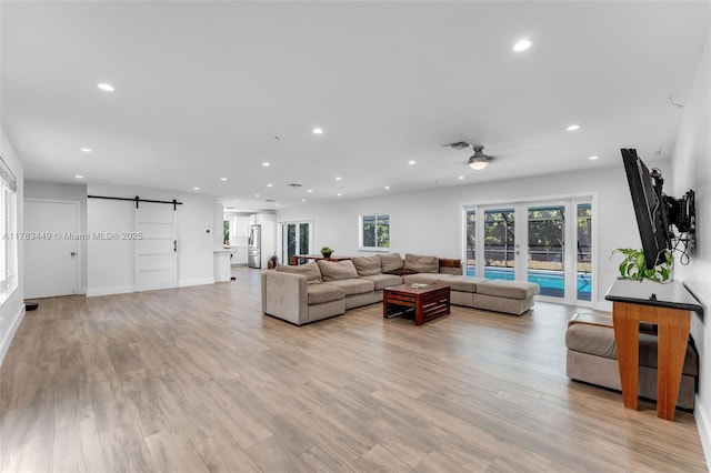 living area featuring recessed lighting, a barn door, visible vents, and light wood finished floors