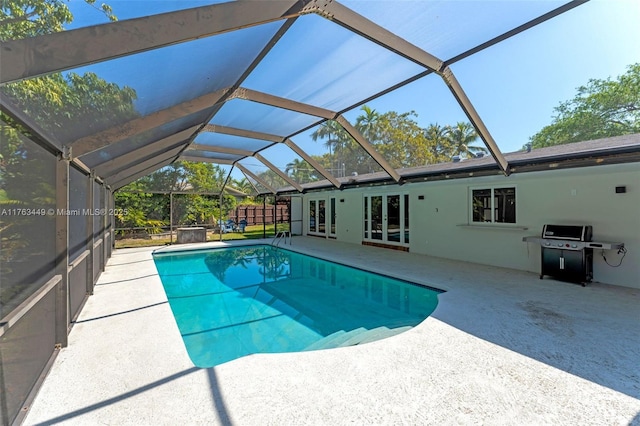 outdoor pool with grilling area, a patio, french doors, and a lanai