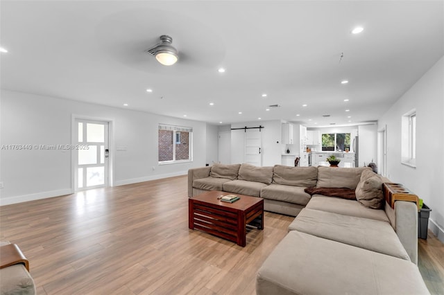 living area featuring recessed lighting, a barn door, light wood-style flooring, and ceiling fan