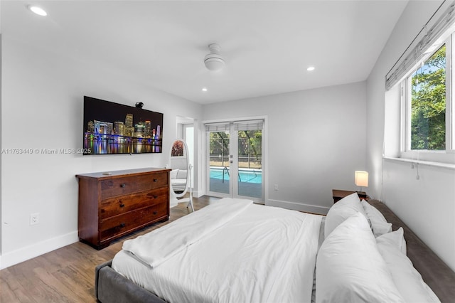 bedroom featuring access to exterior, multiple windows, wood finished floors, and baseboards