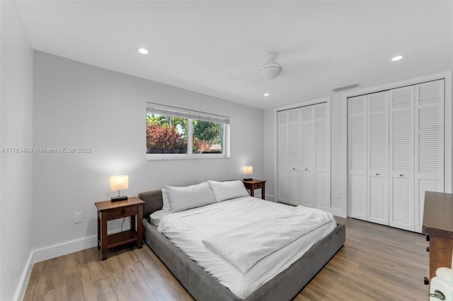 bedroom featuring recessed lighting, baseboards, two closets, and wood finished floors