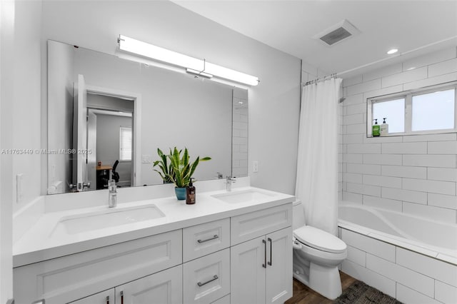 ensuite bathroom featuring double vanity, visible vents, a sink, and toilet